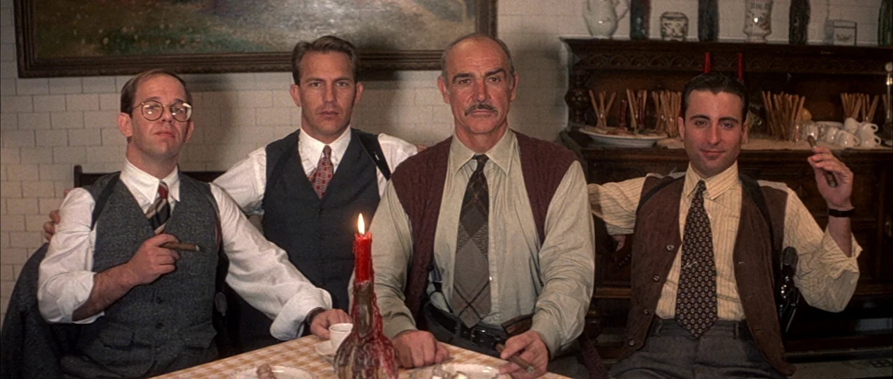 The Untouchables (1987) movie still: medium — A group of four men in 1930s formal wear sit around a table. A red candle is placed in the center…