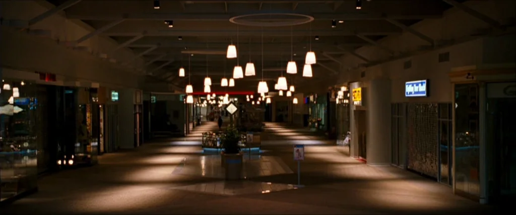 Observe And Report (2009) movie still: establishing — An empty indoor shopping mall walkway features tiled floors and glass storefronts. Numerous…
