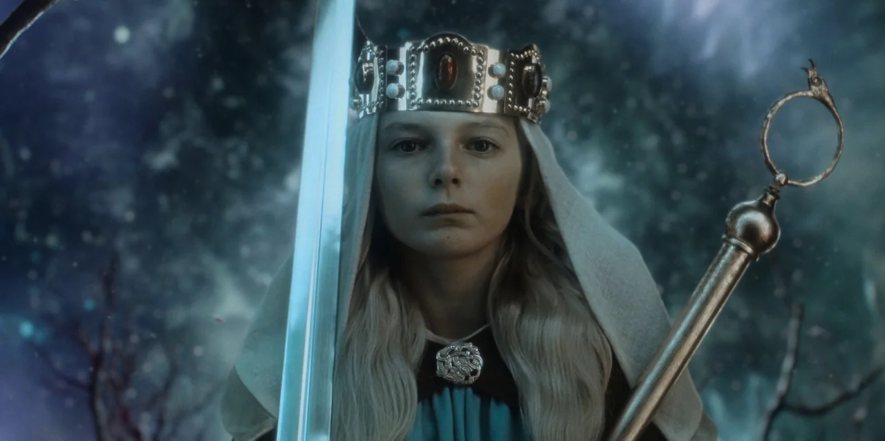 The Northman (2022) movie still: closeup — A young girl with blonde hair stands in a dark, snowy winter forest. She wears a crown and holds a sword…