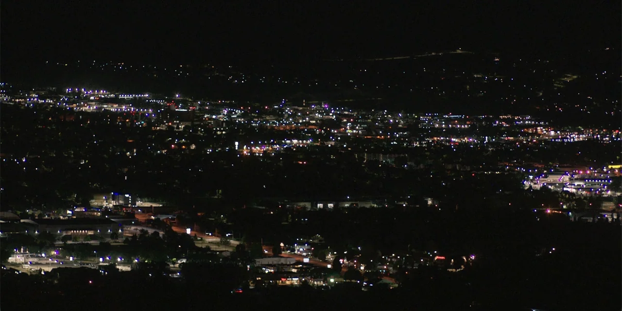 Demonic (2015) movie still: establishing — A wide aerial view of a sprawling urban landscape at night. Numerous artificial light sources from…