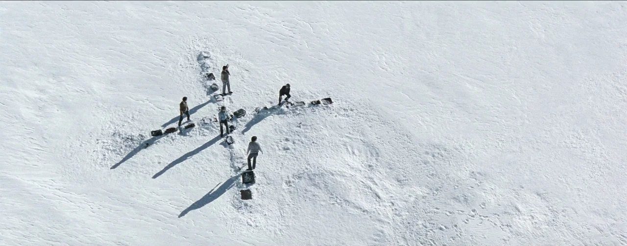 Society of the Snow (2023) movie still: wide — A vast, empty white snow-covered mountainside stretches under bright daylight. A group of five men…