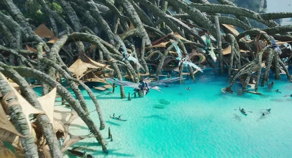 Avatar: The Way of Water (2022) movie still: wide — A vast tropical lagoon features massive, gnarled tree roots dipping into clear turquoise water.…