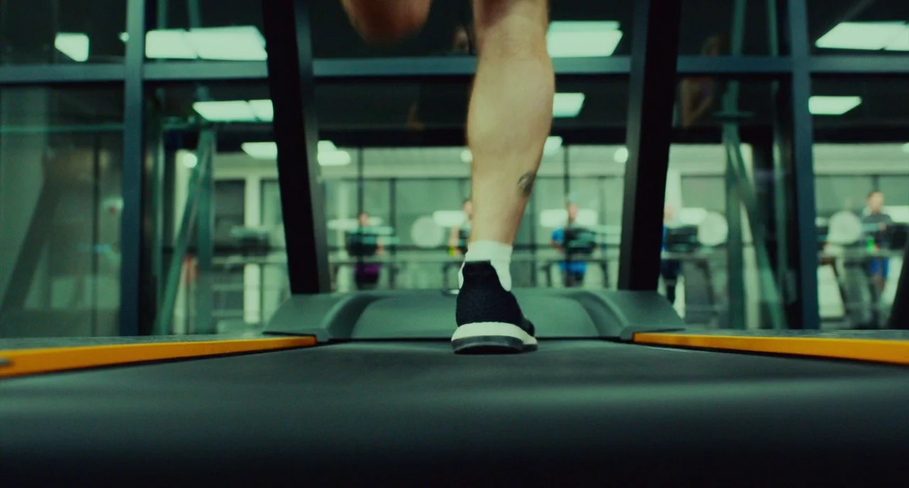 T2 Trainspotting (2017) movie still: closeup — A modern exercise facility interior features dark metal support beams and glass panel partitions. A…