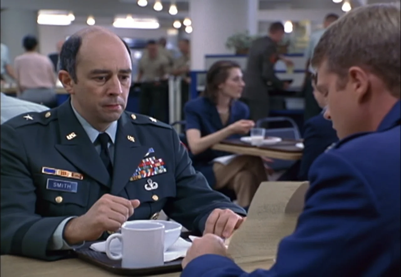 The Pentagon Wars (1998) movie still: medium — A busy military cafeteria contains tables with personnel in uniforms eating and talking. A…