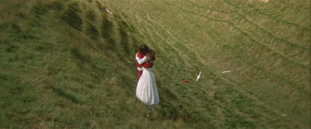 Far from the Madding Crowd (1967) movie still: wide — A sloping green hillside with visible grass textures descends into a shallow valley. A man in…