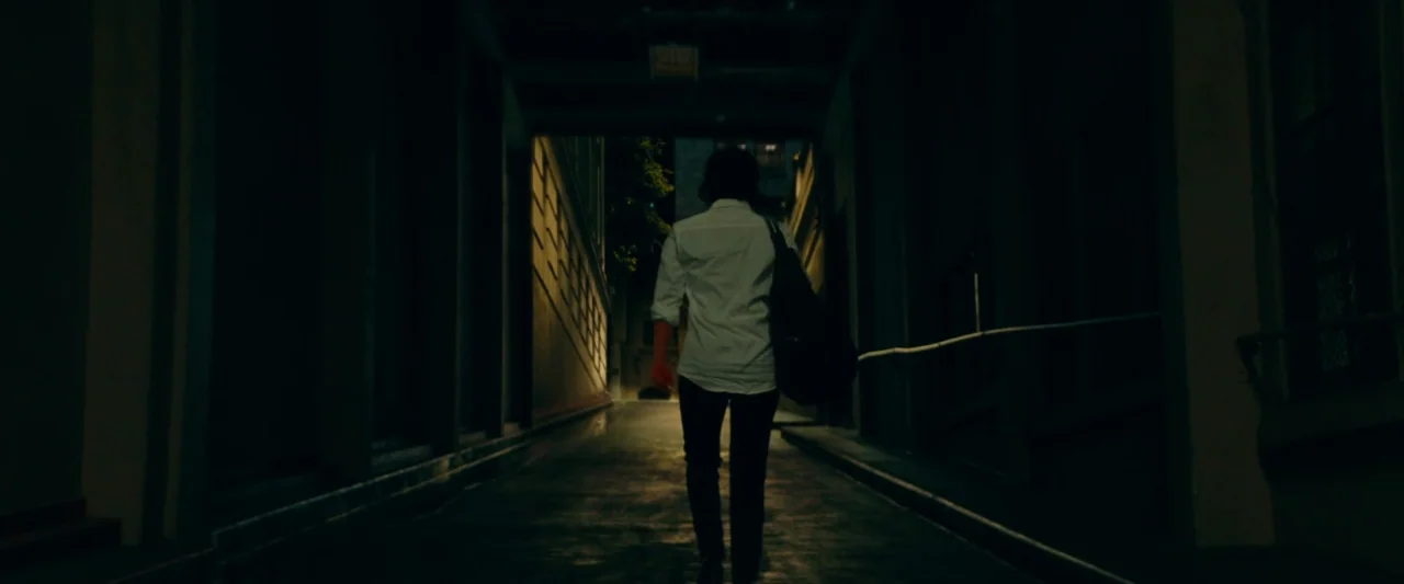 A Star Is Born (2018) movie still: fullbody — A dark, narrow urban alleyway with high walls receding into a patch of light. A person walks forward…