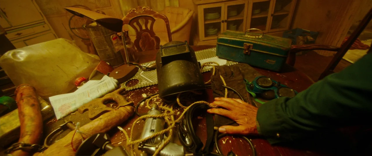 Random Acts of Violence (2019) movie still: medium — A dark wooden workbench is covered in an assortment of worn metal tools. A welding mask and…