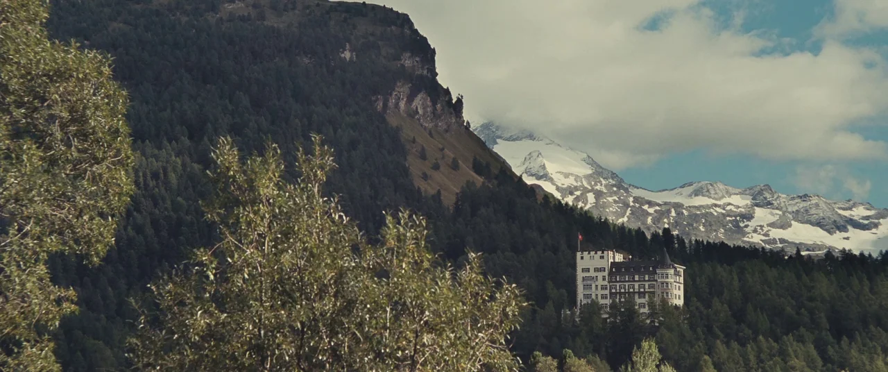Clouds of Sils Maria (2014) movie still: establishing — A large European-style hotel stands amidst a dense coniferous forest on a mountain slope.…