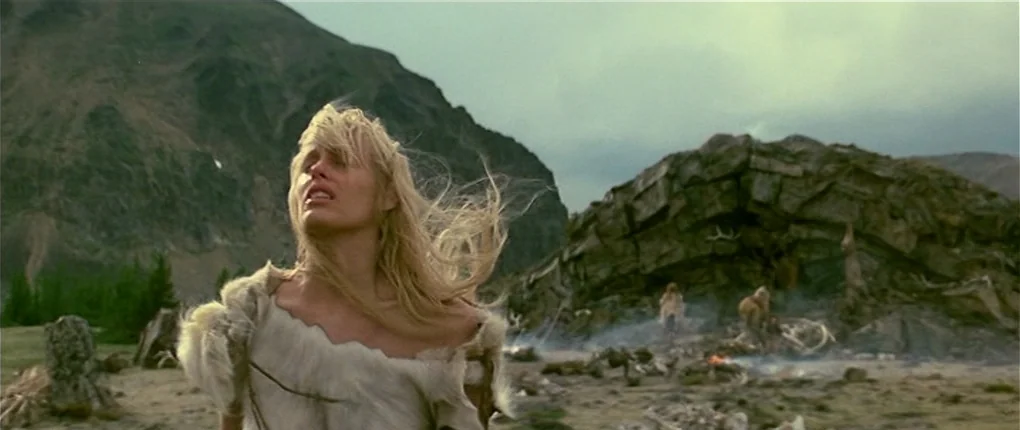 Clan of the Cave Bear (1986) movie still: medium — A rugged mountain landscape features a stony slope and scattered remains of animal bones. A young…