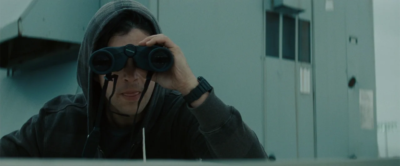 Red Dawn (2012) movie still: medium — A flat grey rooftop with a utility structure stands behind the subject. A young man wearing a grey hoodie…