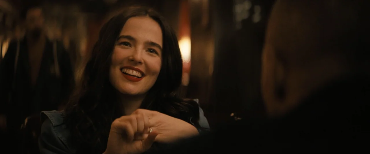 Something from Tiffany's (2022) movie still: medium — A dimly lit restaurant interior features dark wooden surroundings with blurred ambient light.…