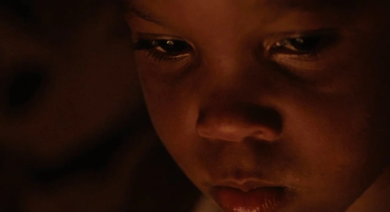 Beasts Of The Southern Wild (2012) movie still: closeup — A dark, interior setting with minimal environmental detail visible behind the subject. A…