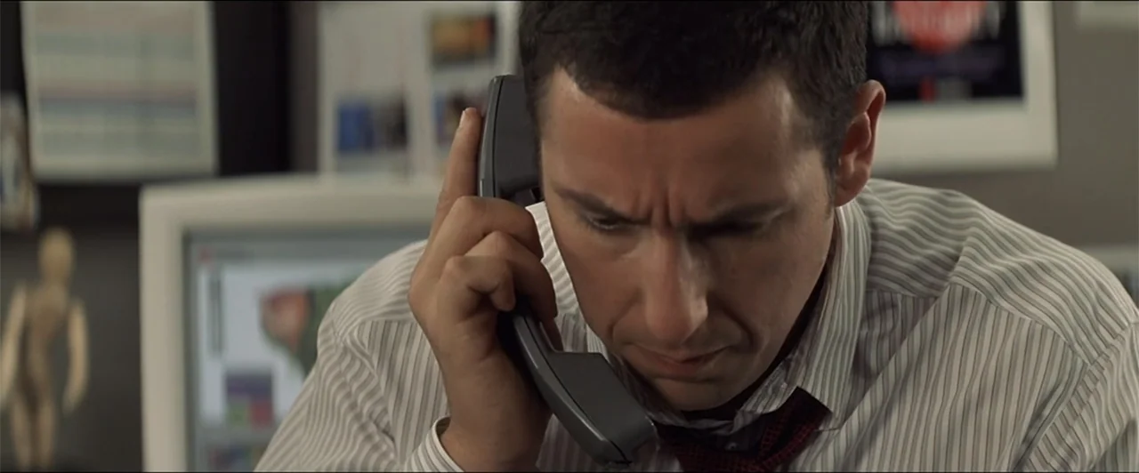 Anger Management (2003) movie still: medium — A modern office environment features office equipment and documentation visible in the out-of-focus…