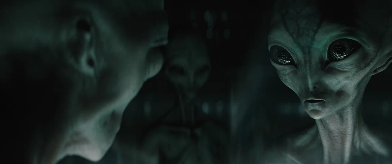 No One Will Save You (2023) movie still: medium — A dark, cramped interior with a cool color palette and metallic textures. Multiple grey alien…