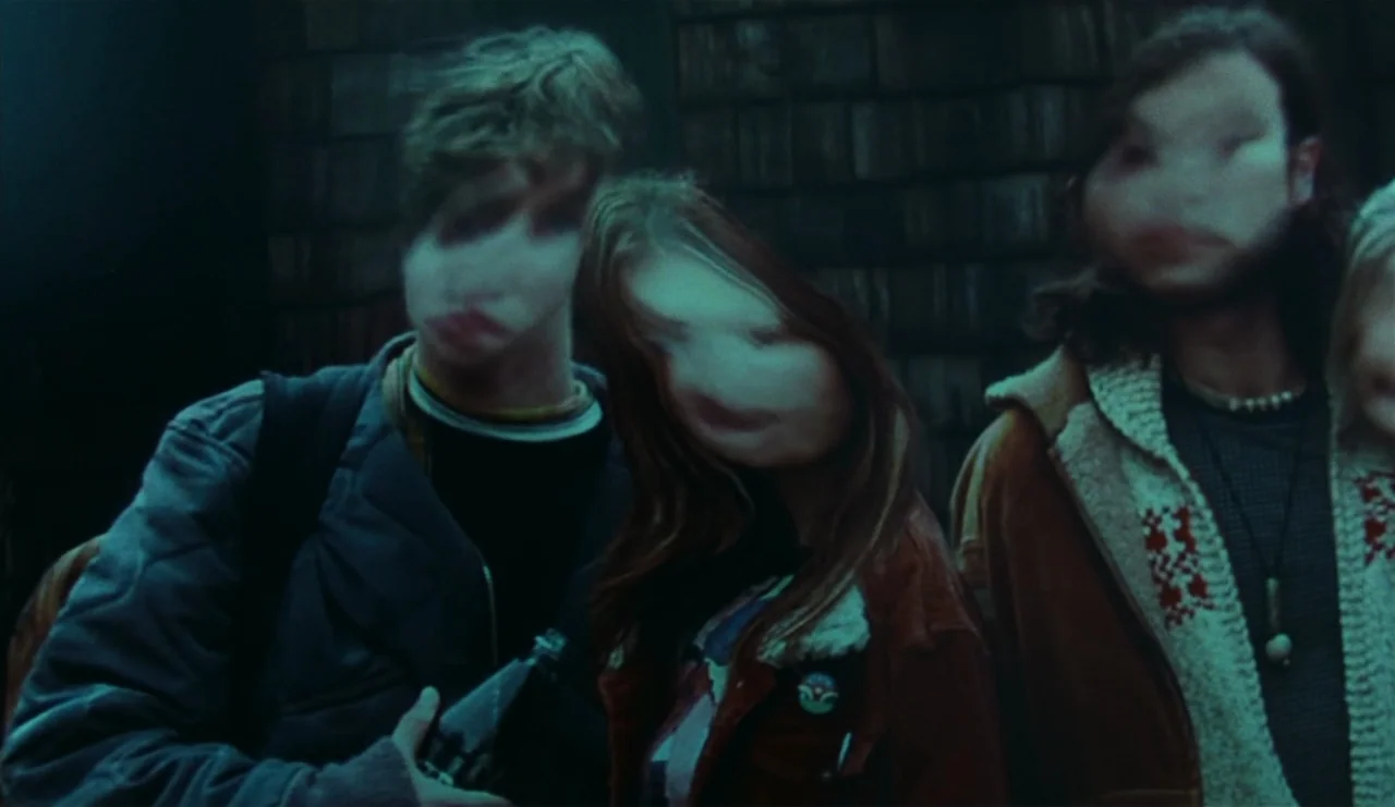 The Ring (2002) movie still: medium — Three teenagers stand in front of dark wood shingle siding at night. Their faces appear blurred and…
