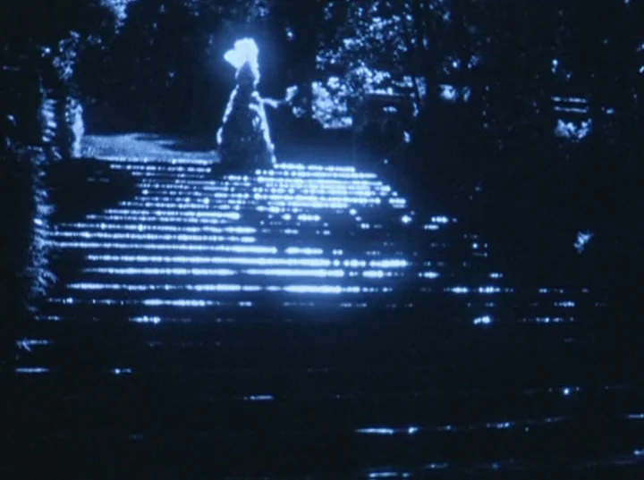 Eaux d’Artifice (1953) movie still: wide — A dark stone staircase is illuminated by sharp moonlight reflecting off its horizontal edges. A lone…