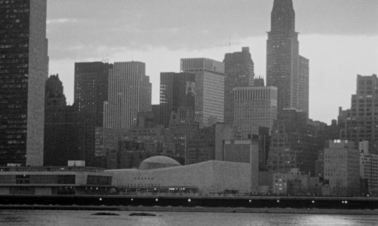 Something Wild (1961) movie still: establishing — A wide view of the Manhattan skyline across the East River during dusk. Several skyscrapers and…