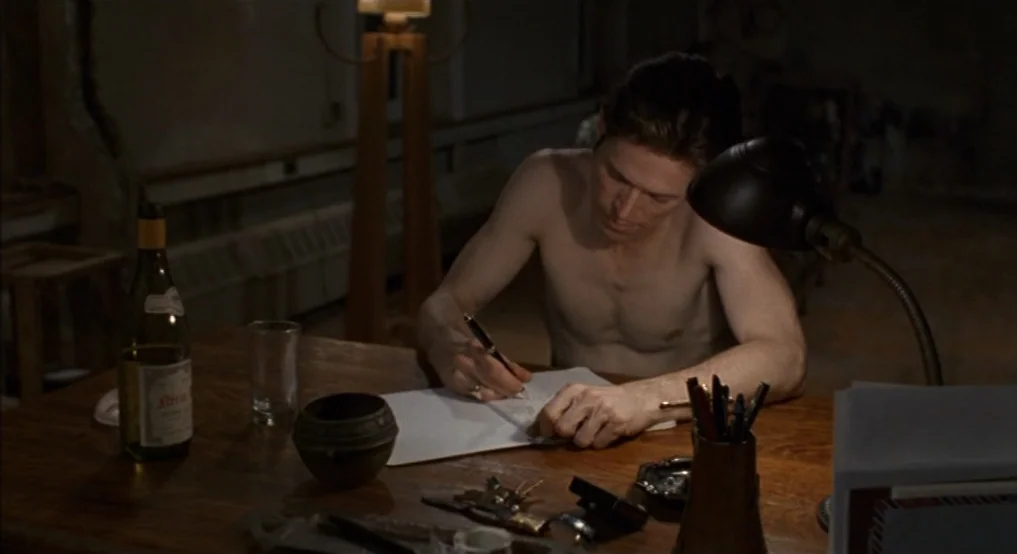 Light Sleeper (1992) movie still: medium — A dimly lit room with a man working at a heavy wooden table. The man sits bare-chested while writing in a…