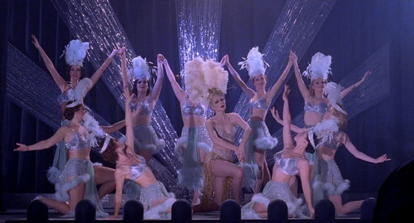 The Man Who Cried (2000) movie still: fullbody — A theatrical stage features nine women performing a coordinated dance with silver costumes. The…
