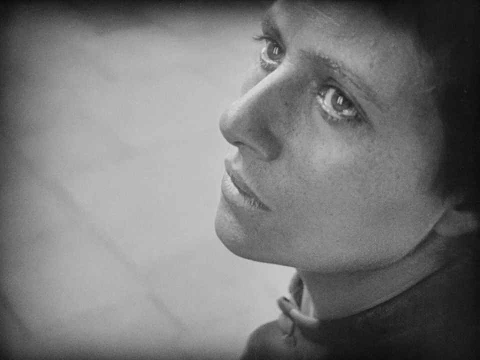 The Passion of Joan of Arc (1928) movie still: closeup — A stark, minimalist space with smooth walls in a silent film. A young woman looks upward…