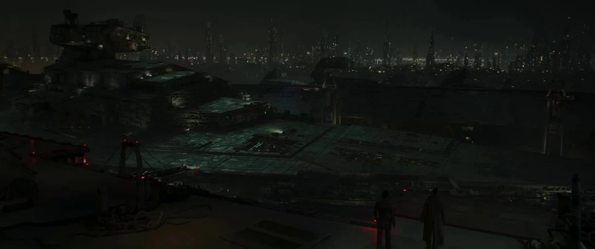 The Mandalorian (2019) movie still: establishing — A dark, expansive spaceport platform overlooks a massive triangular starship and a sprawling…