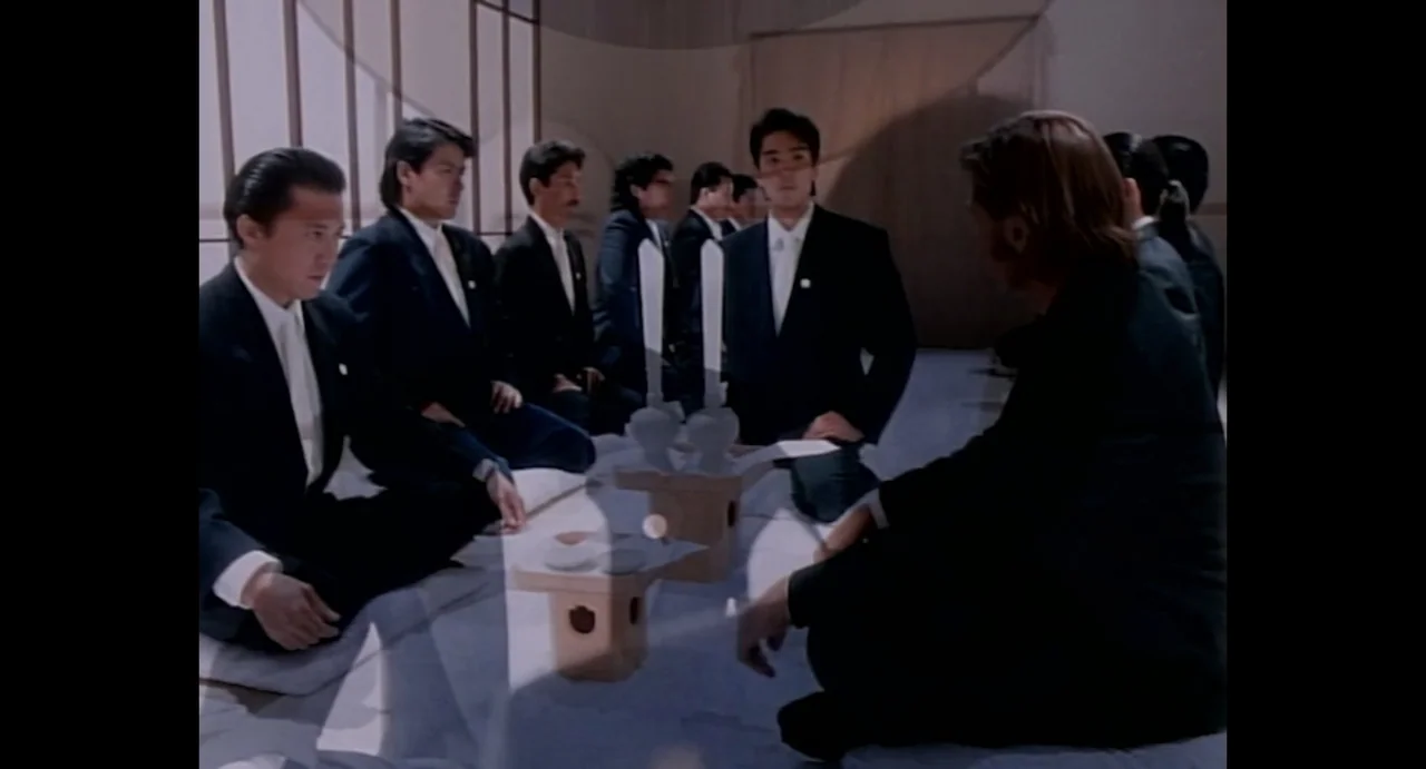 American Yakuza (1993) movie still: medium — A spacious room features minimalist interior design with wood-trimmed paper wall panels. Several men in…