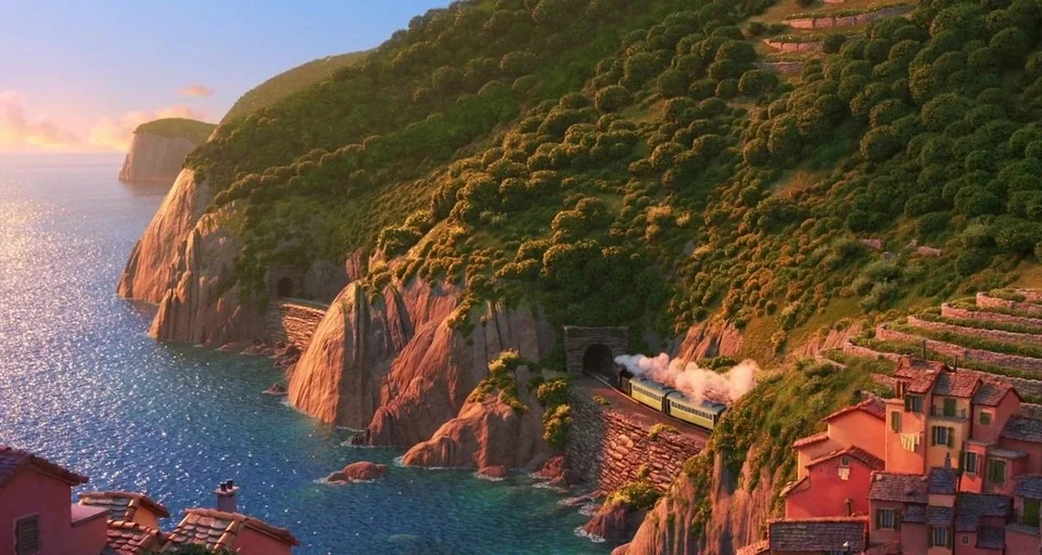 Luca (2021) movie still: establishing — A Mediterranean-style town sits on rocky cliffs overlooking a sparkling blue ocean bay. A steam train…