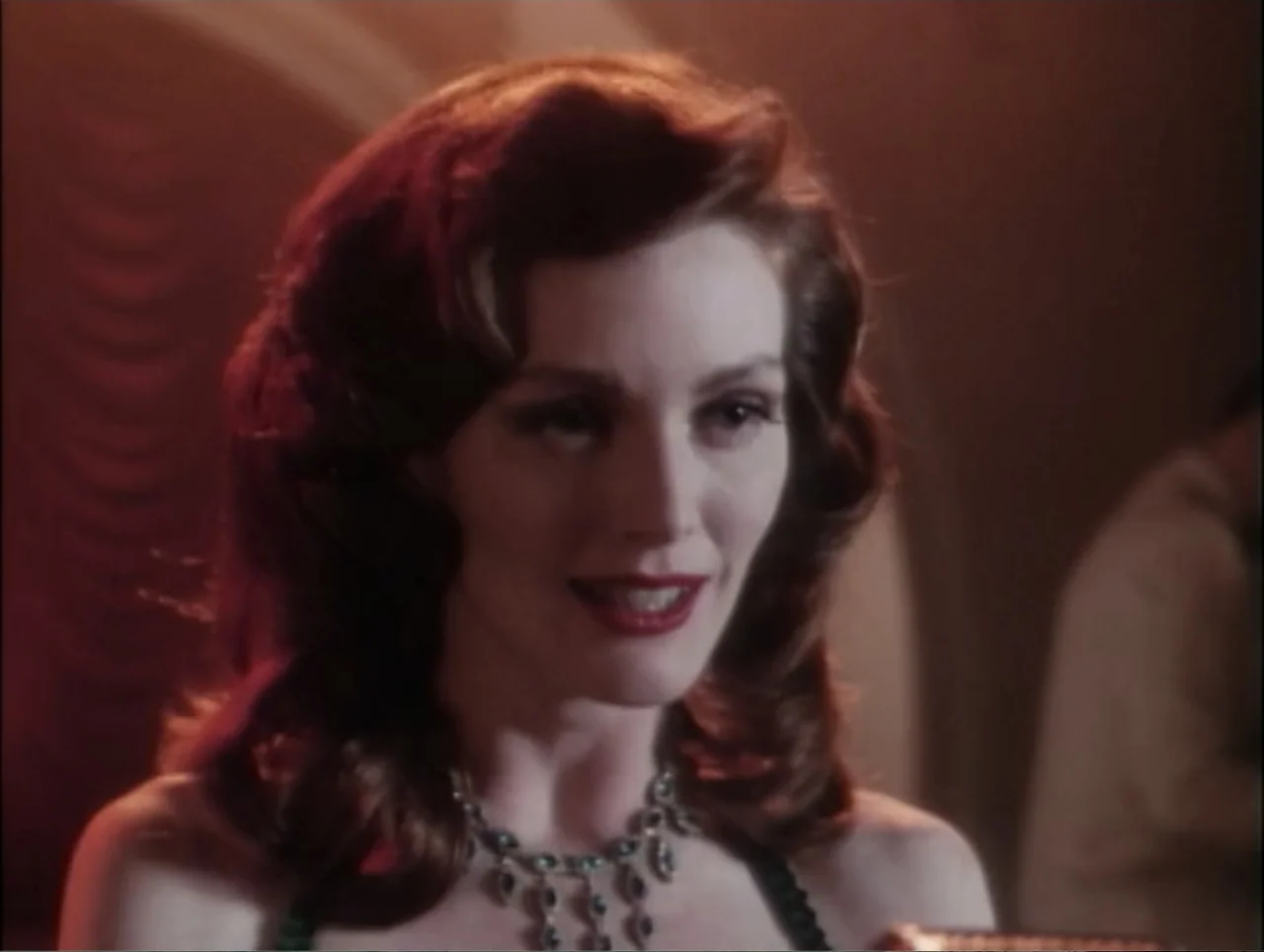 Cast a Deadly Spell (1991) movie still: closeup — A dimly lit nightclub interior features warm background curves and a dark atmosphere. A woman with…