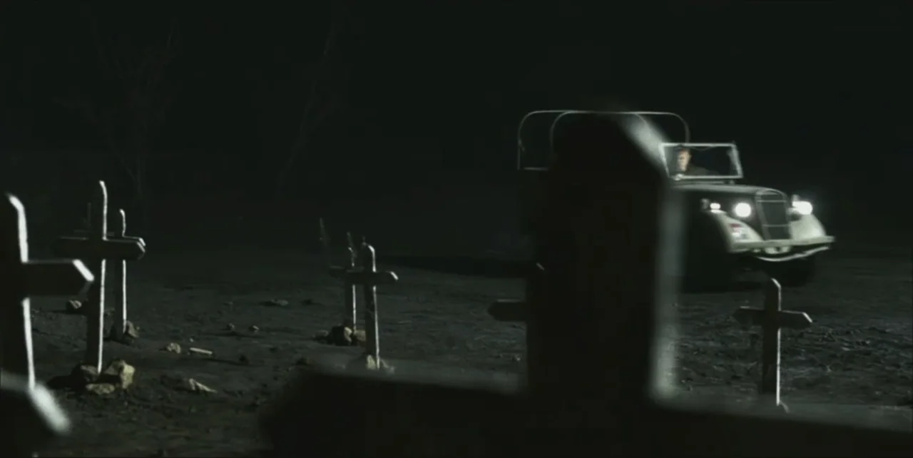 Exorcist: The Beginning (2004) movie still: wide — A nighttime graveyard features multiple wooden grave markers scattered across a dirt landscape. A…