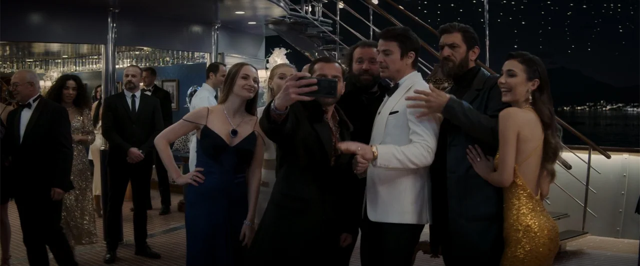 Operation Fortune: Ruse de Guerre (2023) movie still: medium — A group of formally dressed people gather on the deck of a yacht at night. A man…