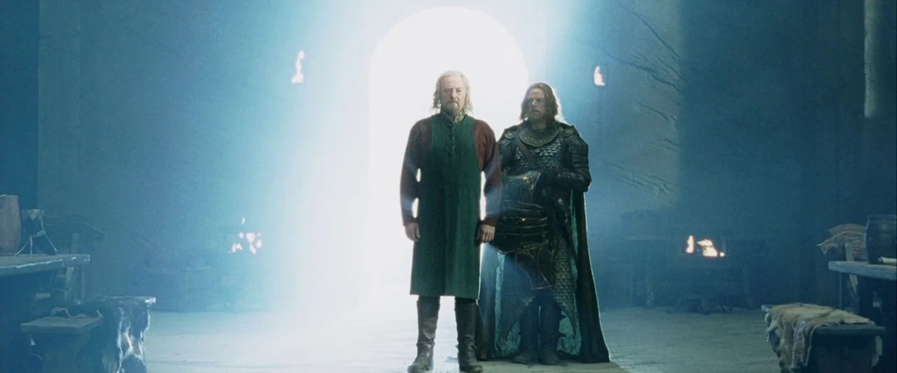 The Lord of The Rings: The Two Towers (2002) movie still: fullbody — A stone-walled interior space with wooden tables and benches situated in the…