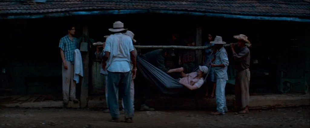 Che Part 1 (The Argentine) (2008) movie still: wide — A group of men in rural clothing stand on a wooden porch at twilight. They are carrying a…