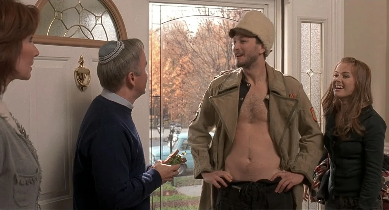 Wedding Daze (2006) movie still: fullbody — An entryway features a white front door with glass panels looking out to autumn trees. A man in a jacket…