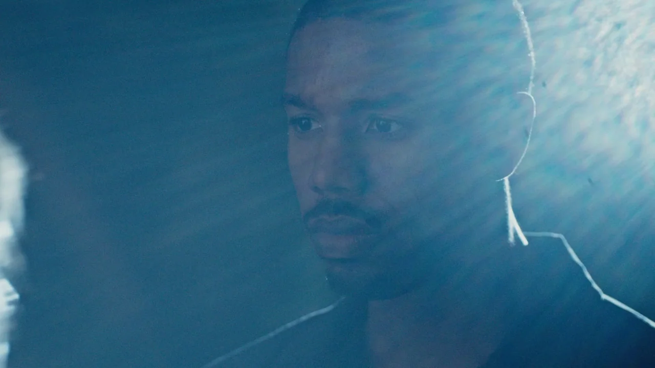 Fahrenheit 451 (2018) (2018) movie still: closeup — A dark, dimly lit interior space with minimal architectural detail visible in the shadows. A man…