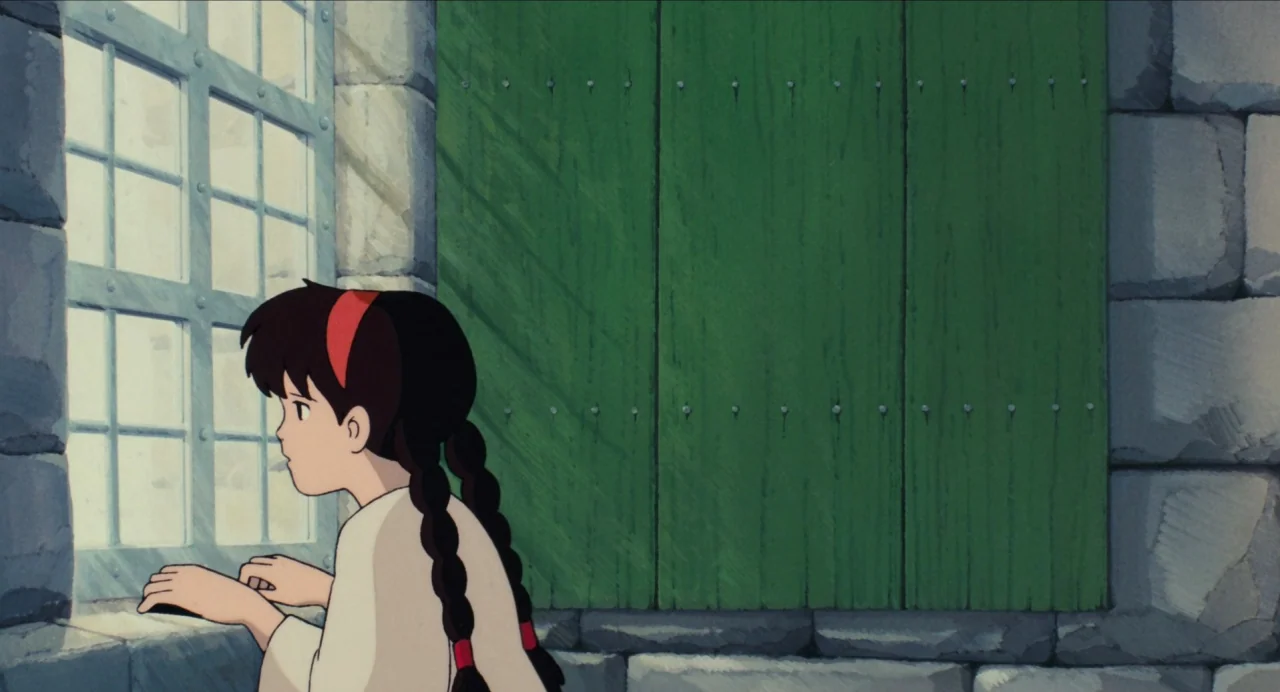 Castle in the Sky (1986) movie still: medium — A room with textured gray stone walls and a green wooden window shutter. A young girl with braided…