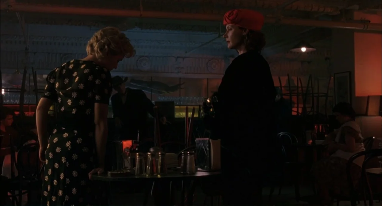 Wild Orchid II: Two Shades of Blue (1991) movie still: medium — A dimly lit diner interior with chairs placed on tables in the background. Two women…