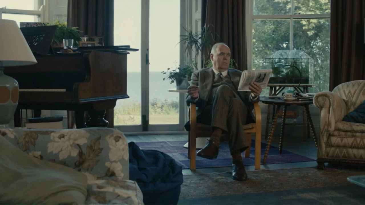 About Time (2013) movie still: medium — A sunlit interior space features a piano, comfortable armchairs, and floor-to-ceiling windows. An elderly…