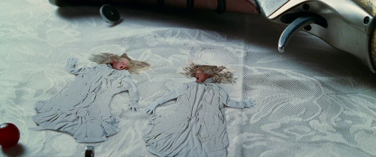 A Hitchhiker’s Guide To The Galaxy (2005) movie still: closeup — A white lace tablecloth rests on a surface next to a metallic object. Two small,…