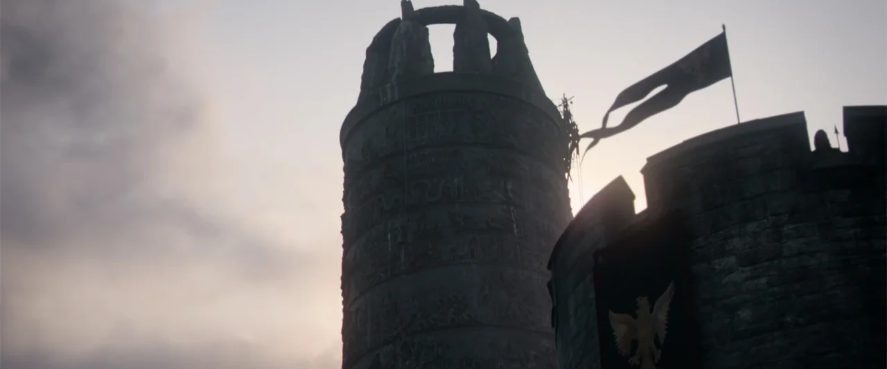 King Arthur: Legend of the Sword (2017) movie still: establishing — A stone tower featuring intricate carvings rises into a pale twilight sky. A…