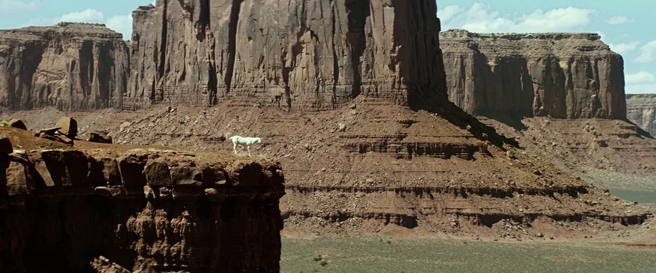 The Lone Ranger (2013) movie still: wide — A vast desert landscape features towering red rock mesas and deep canyon walls. A single white horse…