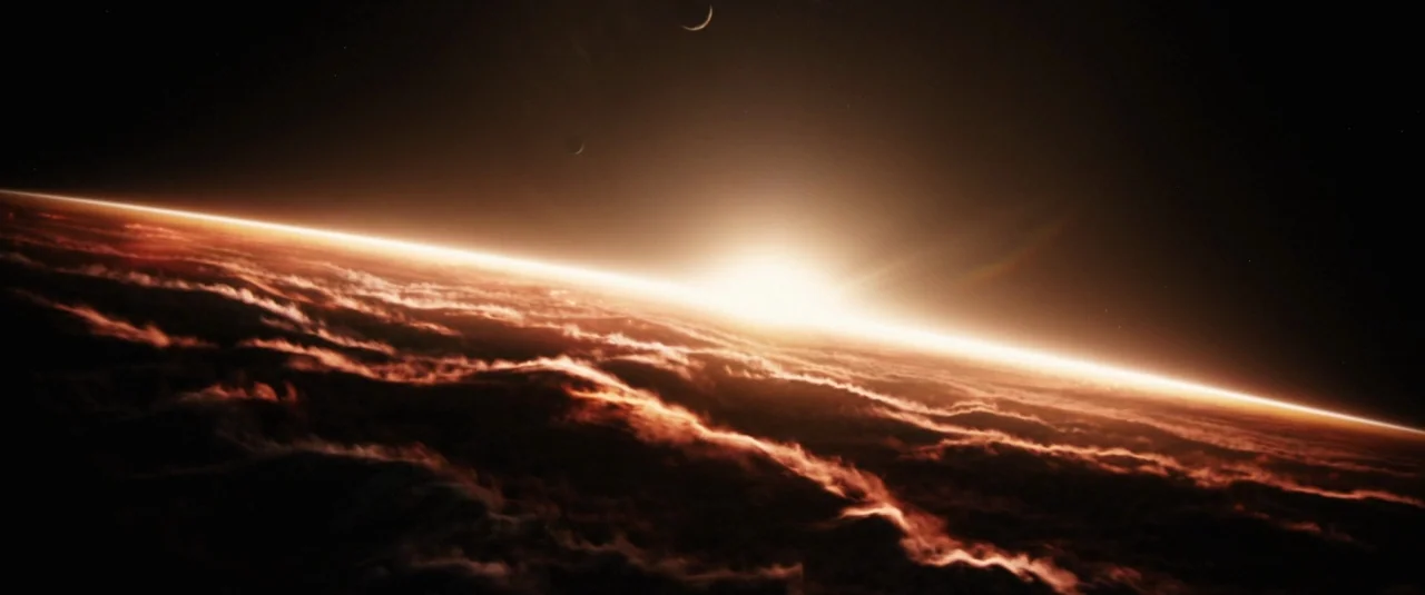 Jupiter Ascending (2015) movie still: establishing — An aerial view of a planetary horizon reveals a massive layer of thick clouds. The sun peeks…
