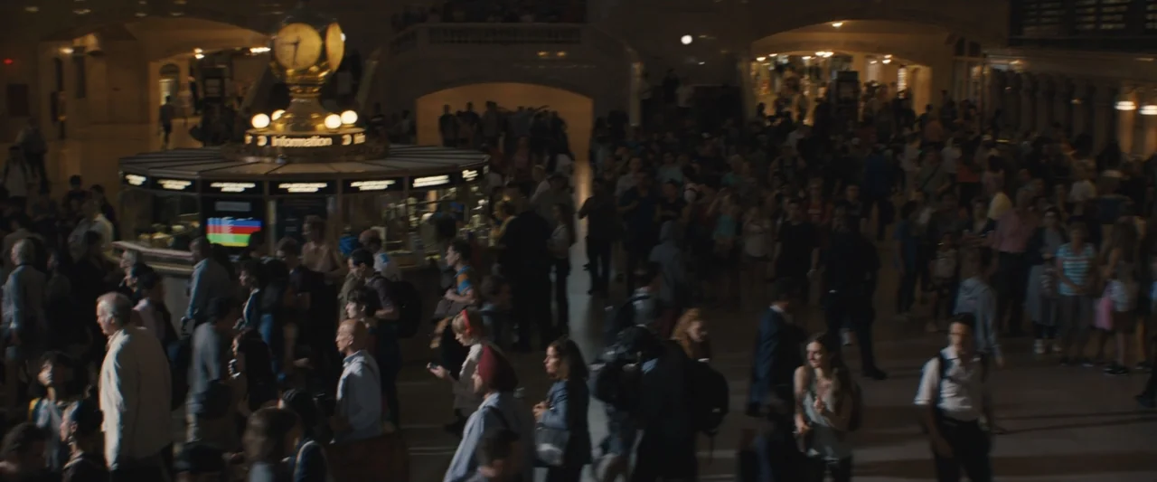 The Sun Is Also a Star (2019) movie still: wide — A bustling grand transit terminal featuring high ceilings and a central information clock kiosk. A…