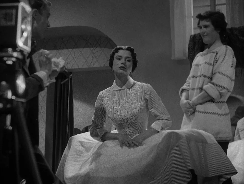 Dreams (1955) movie still: medium — A bright studio space with minimal decor and a visible camera in the foreground. A woman sits for a portrait…