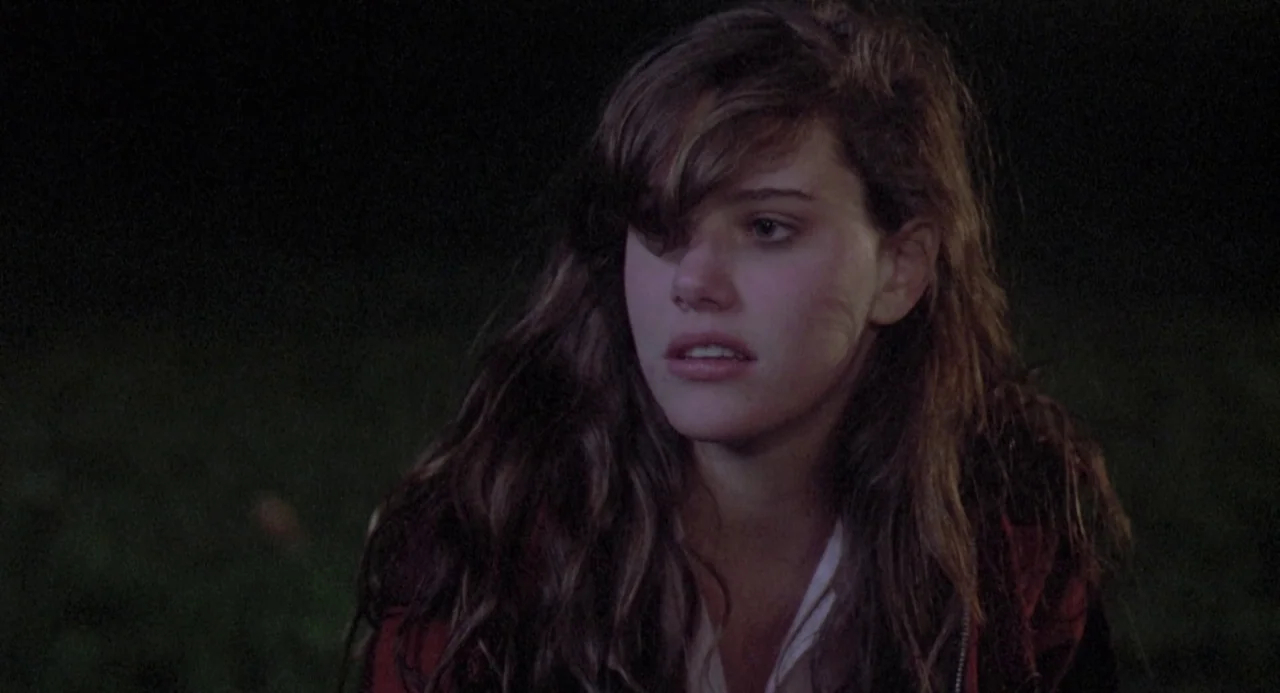 River’s Edge (1986) movie still: closeup — A woman stands in a dark outdoor area at night. She is positioned against an unlit background.