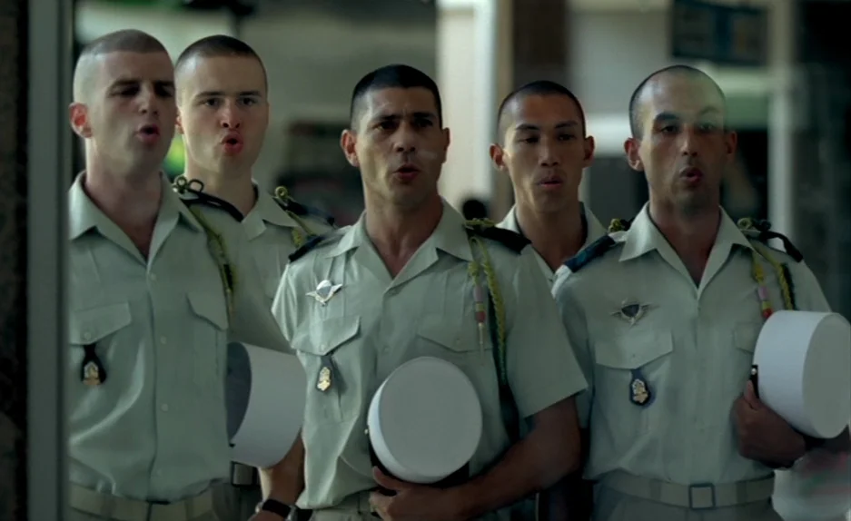 Beau Travail (1999) movie still: medium — Five French Foreign Legion soldiers in uniform stand in a row indoors. They hold cylindrical white hats in…