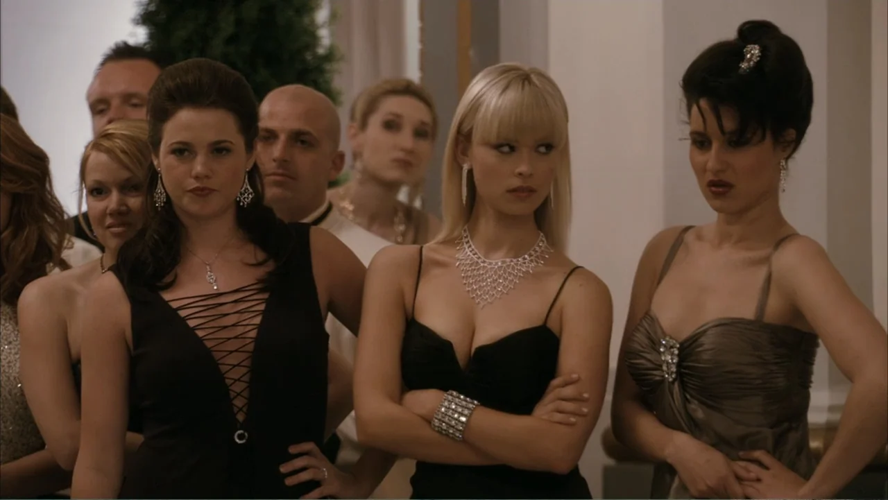 Get Smart (2008) movie still: medium — A well-lit indoor venue with classic architectural pillars and a crowd of guests. Three women in formal…