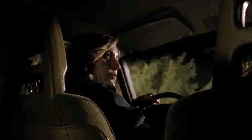 The House Of The Devil (2009) movie still: medium — The dark interior of a car at night features the driver looking ahead. The driver grips the…