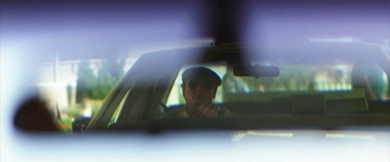 Days of Thunder (1990) movie still: medium — A man drives a car as seen through a reflective rearview mirror. The view is partially obscured by the…