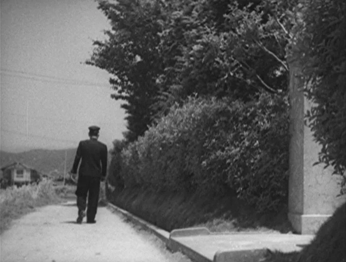 No Regrets for Our Youth (1946) movie still: fullbody — A quiet rural path bordered by a dense, manicured hedge and a tall stone pillar. A man…