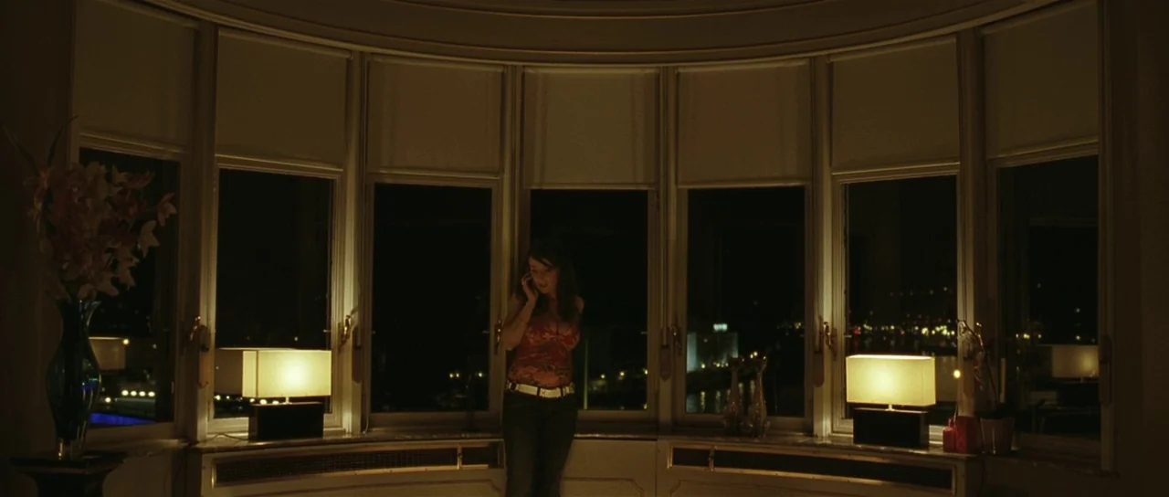 Bullhead (2011) movie still: wide — A curved bay window wall overlooks a dark city at night from an apartment. A woman stands in the center of the…